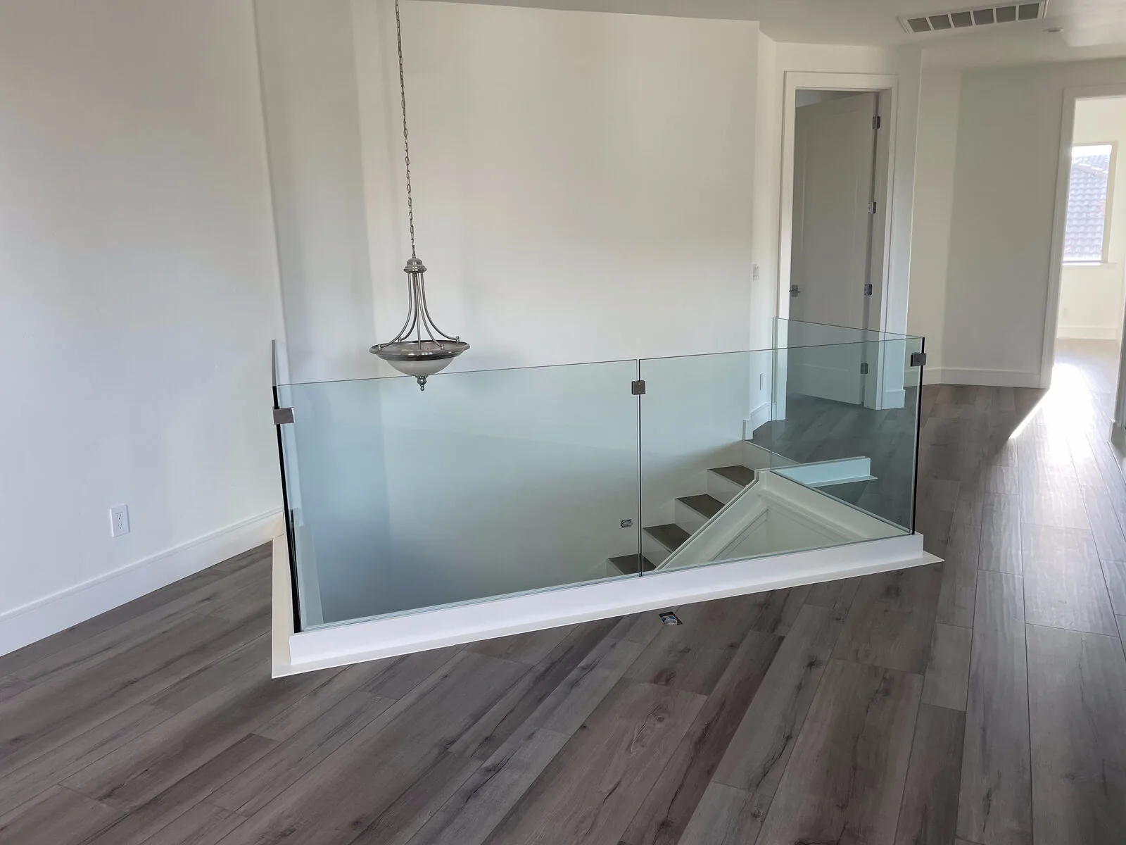 Clamp-mounted tempered glass panels running along the upstairs landing