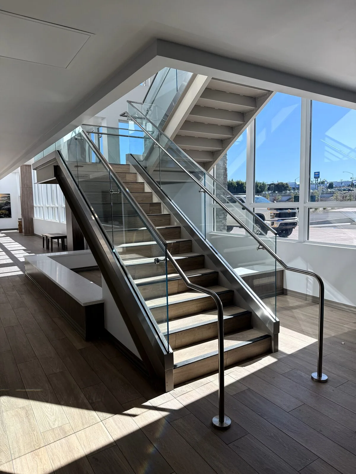 Glass-railed staircase rising through the health care building's daylight-filled stairwell