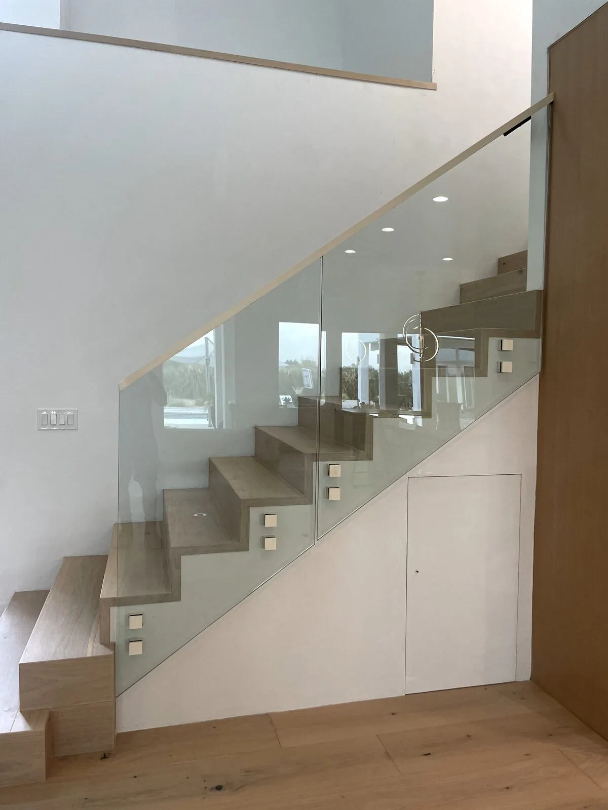 Floating white oak stairs with a standoff-mounted frameless glass railing in a Livermore home